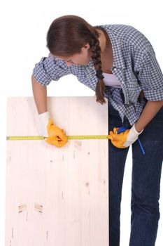 woman carpenter with wooden plank and measuring tape 