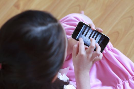 Little girl playing piano on  modern touch screen phone