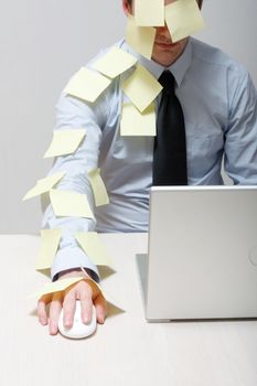 A man covered in yellow notes by a laptop