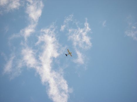 portrait of a small airplane flying in blue cloudy sky
