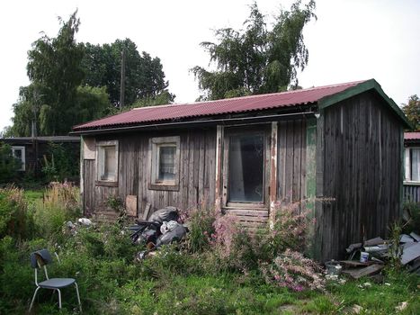 portrait of old abandon house and trash around
