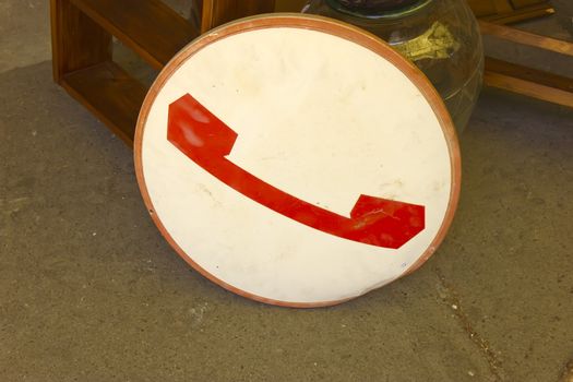 An old round sign with telephone symbol advertising public phone.