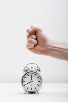 A hand breaking an alarm clock