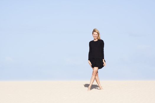 Beautifull girl in black dress posing on the sand dune.