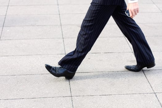 A business man walking with a phone in his hand