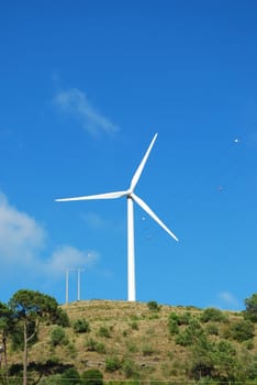 photo of a wind turbine with sky background on a green mountain
