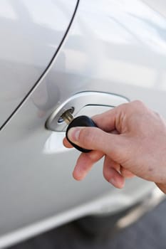 A hand opening a car door with a key