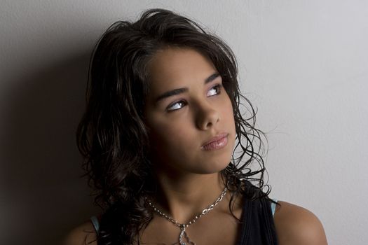 Young woman against a white wall looking up