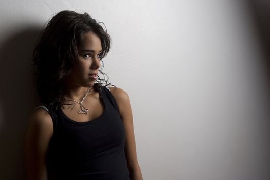 Young woman in black tank top against a white wall 