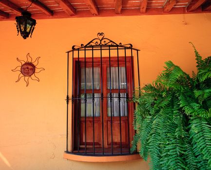 Old fashioned stucco wall with window, grille, sun design and lamp