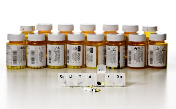 Row of drug bottles with an open tablet box in the foreground