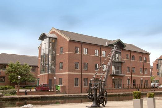 Red Brick Office Block by a canal in Yorkshire under a blue sky with an antique crane in the foreground