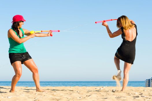 Girls with water pistols fooling around on the beach