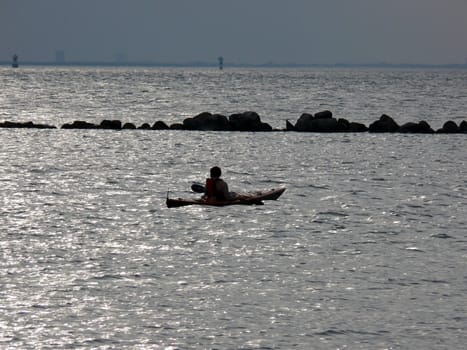 portrait of man in kayak watching ocean landscape in sunset
