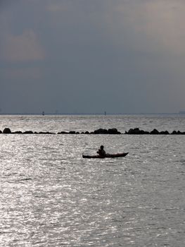 portrait of man in kayak watching ocean landscape in sunset