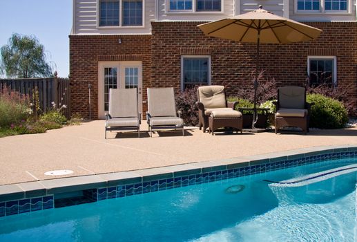 Swimming pool with relaxing seats and sun umbrella providing shade