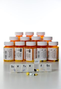 Vertical row of prescription drug bottles with a tablet holder in focus
