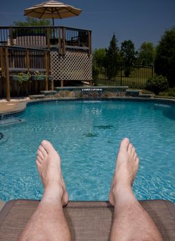 Vertical format of middle aged legs overhanging a swimming pool