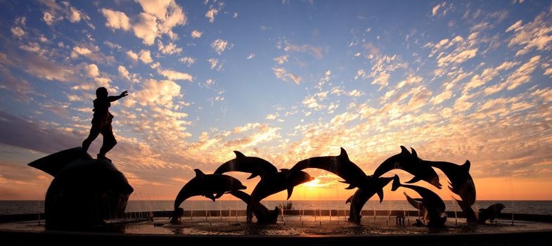 Dolphin statue in Mazatlan frames a beautiful sunset over the ocean