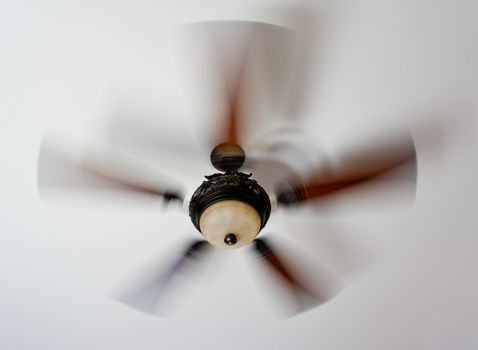 An ornate spinning ceiling fan with glass light