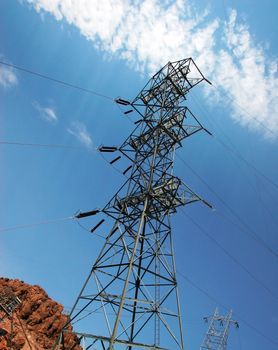 View upwards towards the top of an electric pylon against blue sky