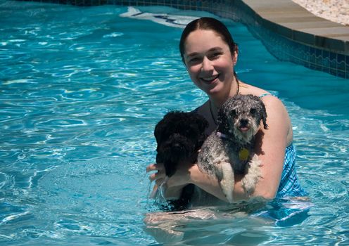 Woman and two small dogs in her arms in a blue swimming pool