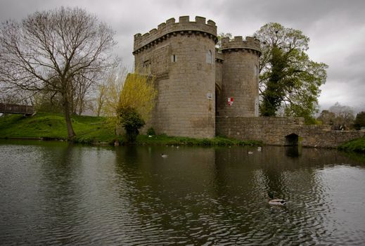 Reflection of Whittington Castle in the moat with ducks swimming by