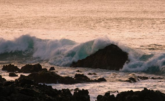 Waves off the coast of Hawaii crashing on rocks at sunset