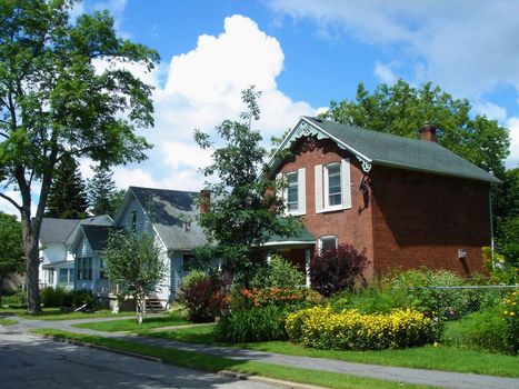 Houses and their beautiful garden in Gananoque, Ontario, Canada, along the street by cloudy weather.