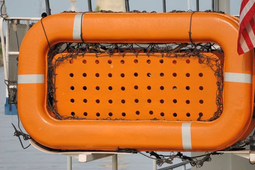An orange lifeboat mounted on the back of a ship.