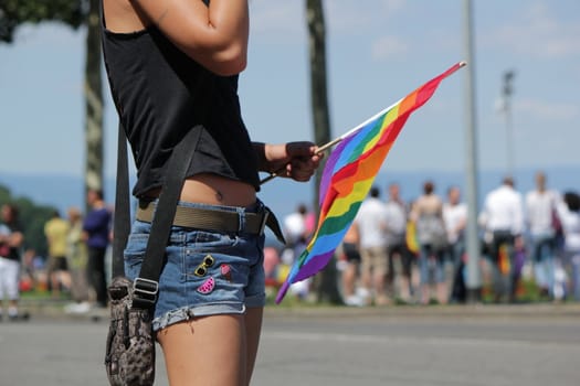 Close up of a woman wearing shorts and holding a rainbow flag at the Gay Pride 2011, Geneva, Switzerland.