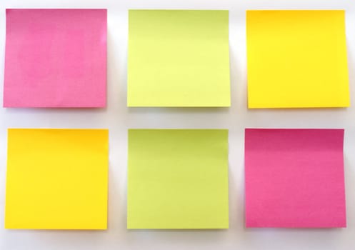 Six multicolored sticky notes stuck on a white wall.