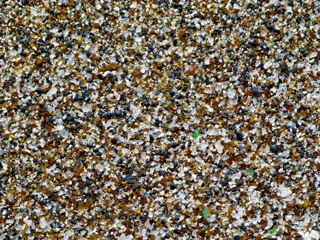 Pattern or background made up of close-up of glass fragments on beach