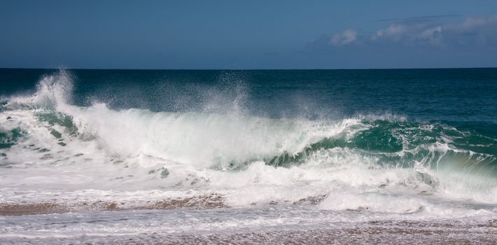 Strong waves breaking onto the sandy beach on north shore of Kauai