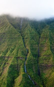 Waterfall streaming down the rock face off Mt Waialeale in Kauai in Hawaii