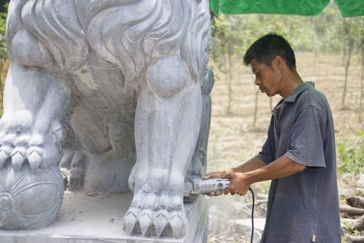 Image of a Chinese craftsman sculpturing a stone lion at Guilin, China.