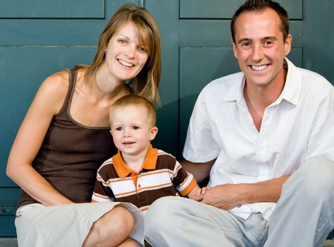 Happy perfect young family with dad, mom and son outdoors having fun