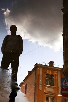 Reflection of a building, clouds and men in water