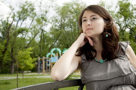 The portrait of the beautiful pregnant woman, sits on a bench