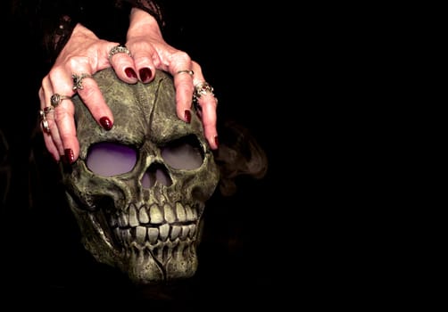 A Halloween prop skull with fog coming from it's eyes and nose being held by a woman's hands.