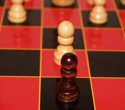 Two pawns face off on a red and black chess board