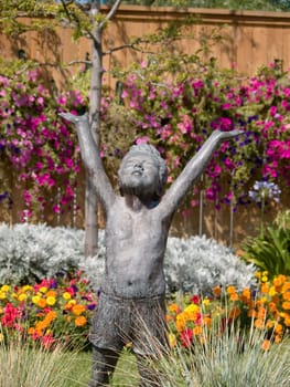 A joyful garden statue of a child in shorts.