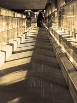 Moving walkway in an airport, with light streaming in in sepia