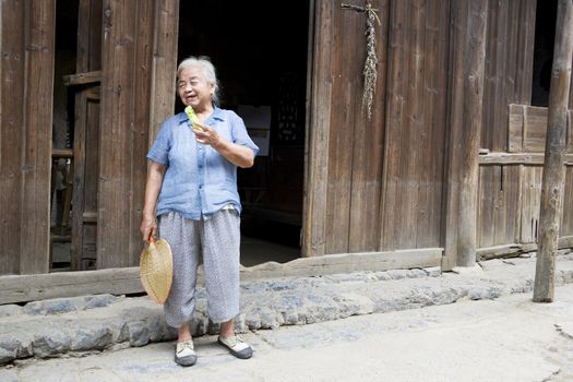 Image of an elderly Chinese lady eating cucumber at Daxu Ancient Town, Guilin, China.