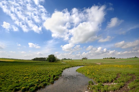 Small river, framland and blue and cloudy sky.