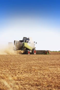 A combine harvester machine at work bringing in the rape seed harvest. Location in Rural Wiltshire, uk england.