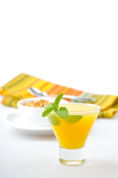 Glass of fresh orange juice garnished with a sprig of mint.