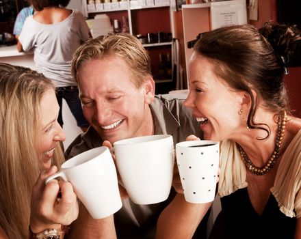 Three friends in a coffee house toasting with their cups