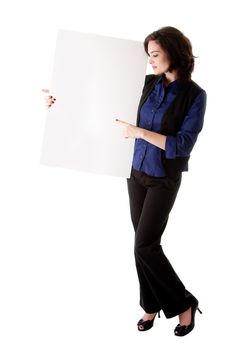 Happy smiling beautiful young caucasian brunette business student woman standing next to and holding a white blank board and pointing at it, isolated