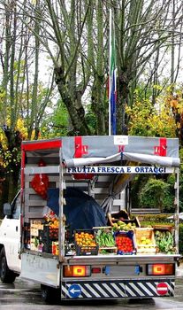 A fruit and vegetable truck awaits customers in a Tuscan town piazza (square).